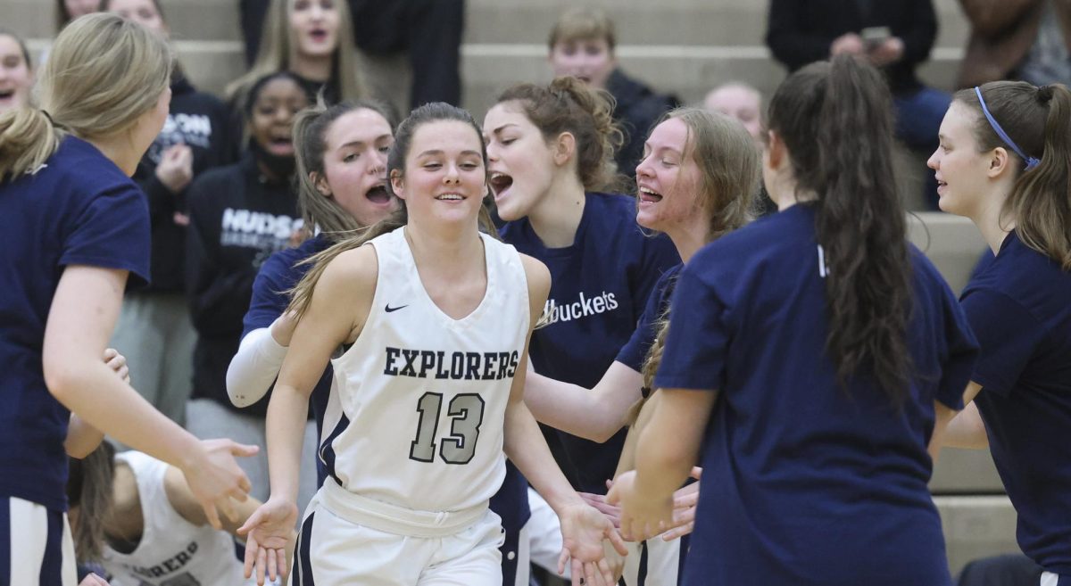 A senior on the Girls Basketball team high-fives her teammates while wearing an Explorers jersey. Used with permission/Ken Klemencic.