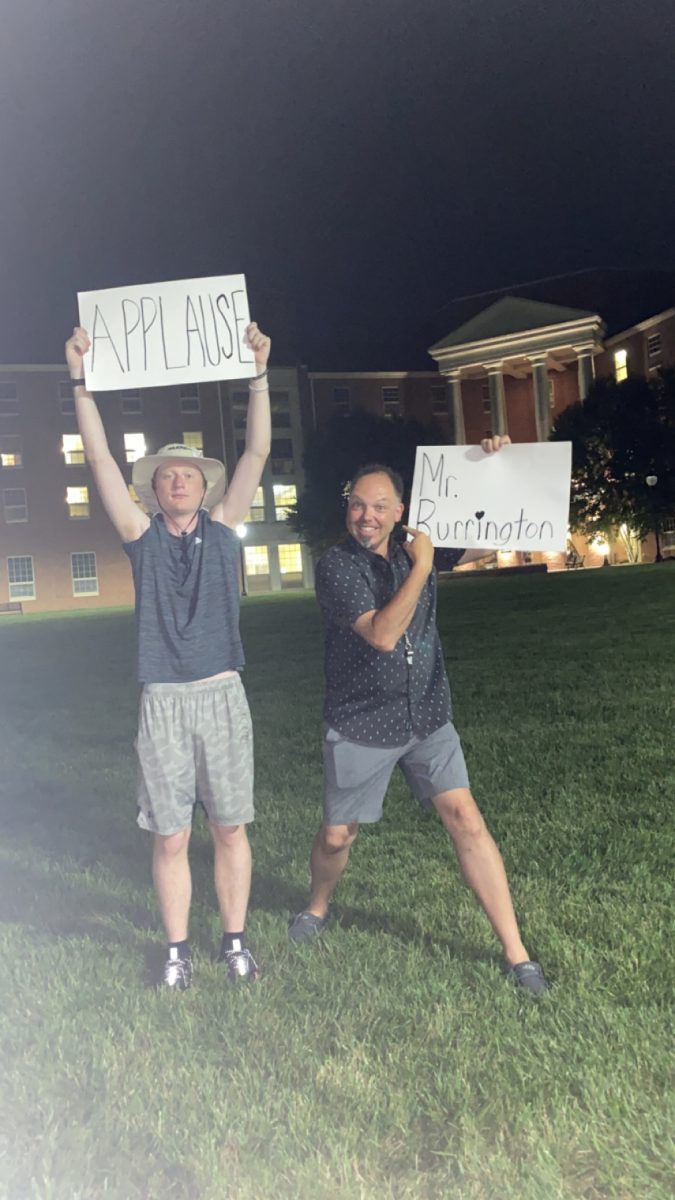 Senior Jason Dement and Assistant Band Director John Burrington hold up signs during during band camp, which is held every year for members of the Hudson Swing Marching Band during the summer at Marietta College. 